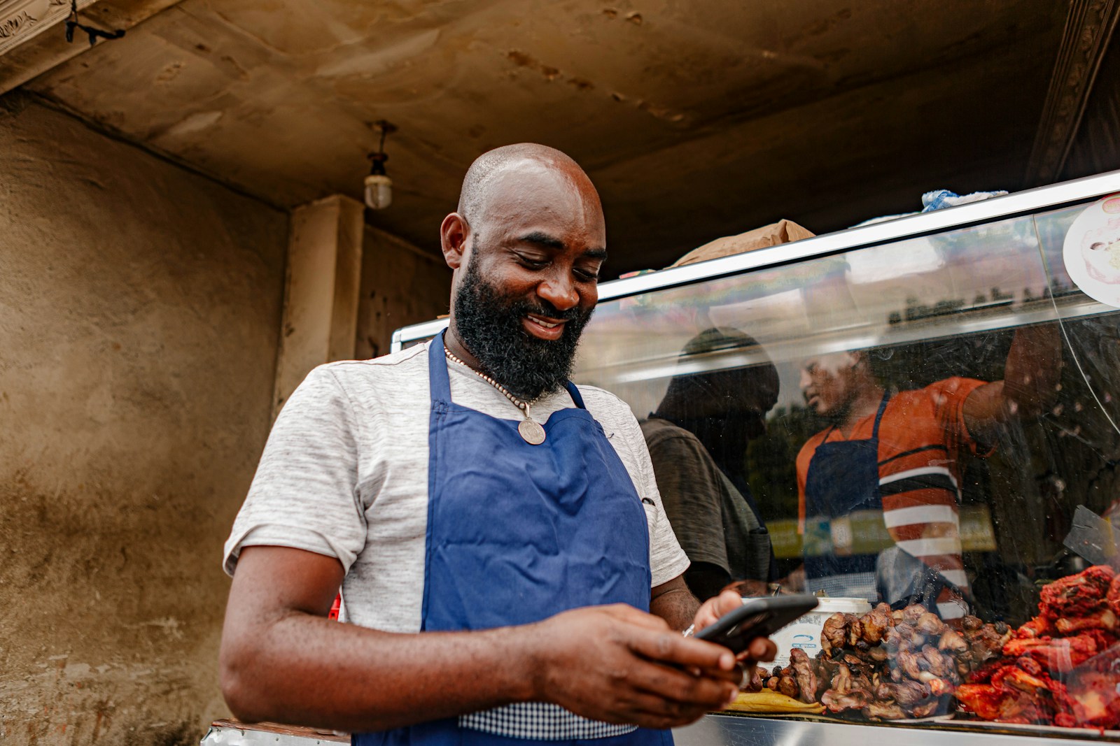 Lagos suya vendor at his stall checking customer messages on his phone
